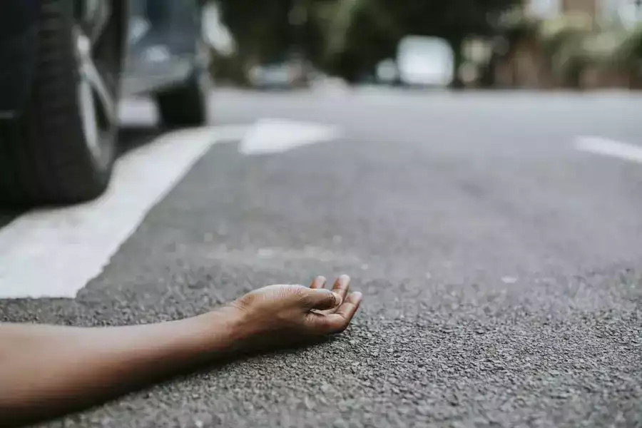 person lying on the ground after a car accident